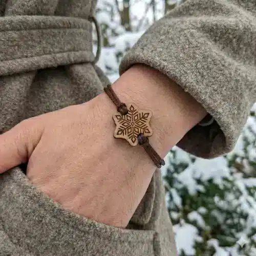 Snoo wooden bracelet, snowflake design with recycled PET cord worn on a woman's wrist