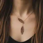 collier-en-bois-ekinox-1-4 Collier Ekinox en bois avec pendentifs feuilles en bois suisse sur chaîne dorée, porté sur la poitrine d'une femme avec cheveux bruns
