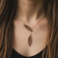 Ekinox wooden necklace with Swiss wooden leaf pendants on a gold chain, worn on the chest of a woman with brown hair