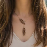 Ekinox wooden necklace with two Swiss wooden leaf pendants on a gold chain, worn on the chest of a woman with light brown hair