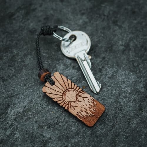Porte clés en bois suisse avec design de paysage montagneux et soleil