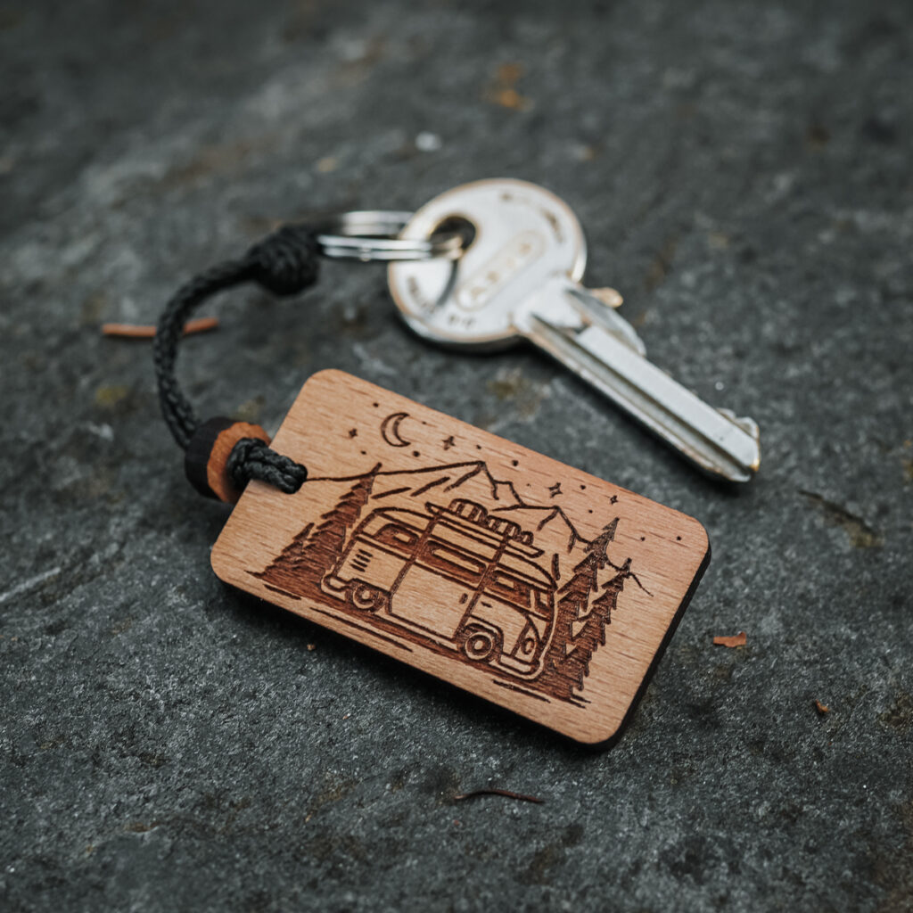 Nuove funzionalità 13 Portachiavi in legno svizzero con design vanlife nella foresta con montagne sullo sfondo