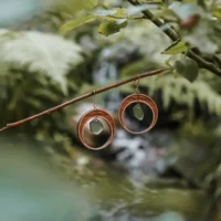 Orecchini a forma di mezzaluna realizzati in legno e vetro riciclato con un vetro verde