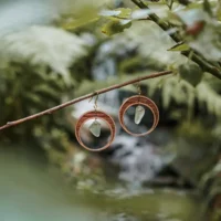 Orecchini a forma di mezzaluna realizzati in legno e vetro riciclato con un vetro verde chiaro