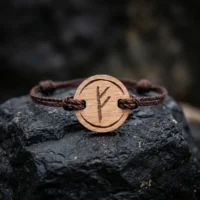 bracelet-en-bois-viking-fehu-1 Bracelet en bois suisse au design de rune viking fehu posé sur une roche