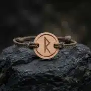 Bracelet en bois suisse au design de rune viking raidho posé sur une roche