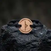 Bracelet en bois suisse au design de rune viking thurisaz posé sur une roche