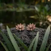 Ohrstecker aus Holz mit einer Lotusblume, die auf einem Stück Holz vor einem Teich ruht