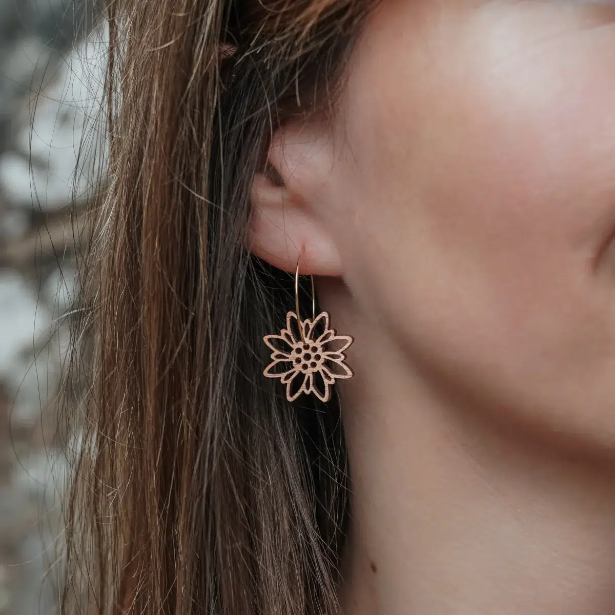 Boucles-oreilles-en-bois-edelweiss-2 Boucles d'oreilles en bois au design d'Edelweiss avec anneaux dorés portés par une femme