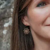 Boucles-oreilles-en-bois-edelweiss-3 Boucles d'oreilles en bois au design d'Edelweiss avec anneaux noirs portés par une femme
